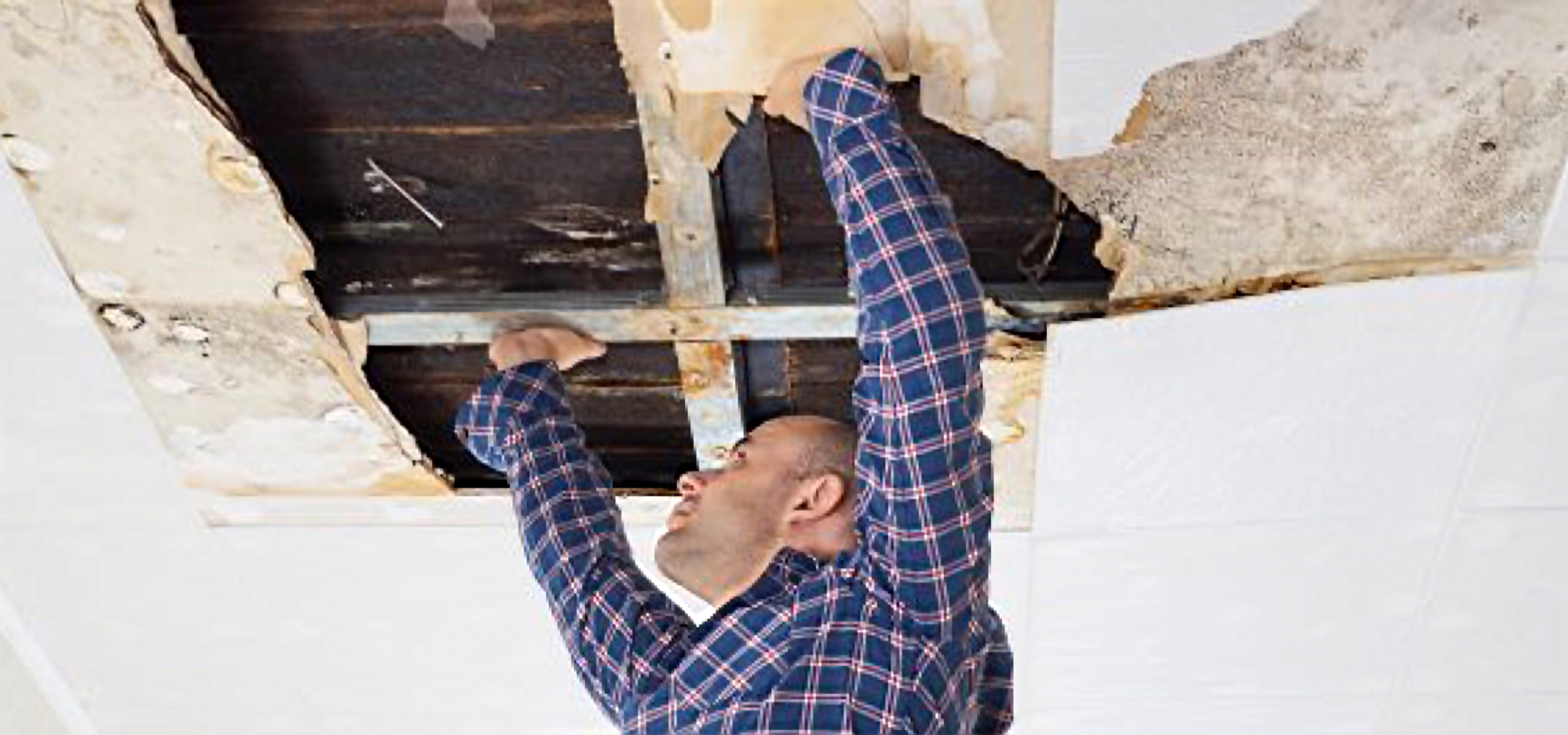 technician inspecting ceiling with water damage